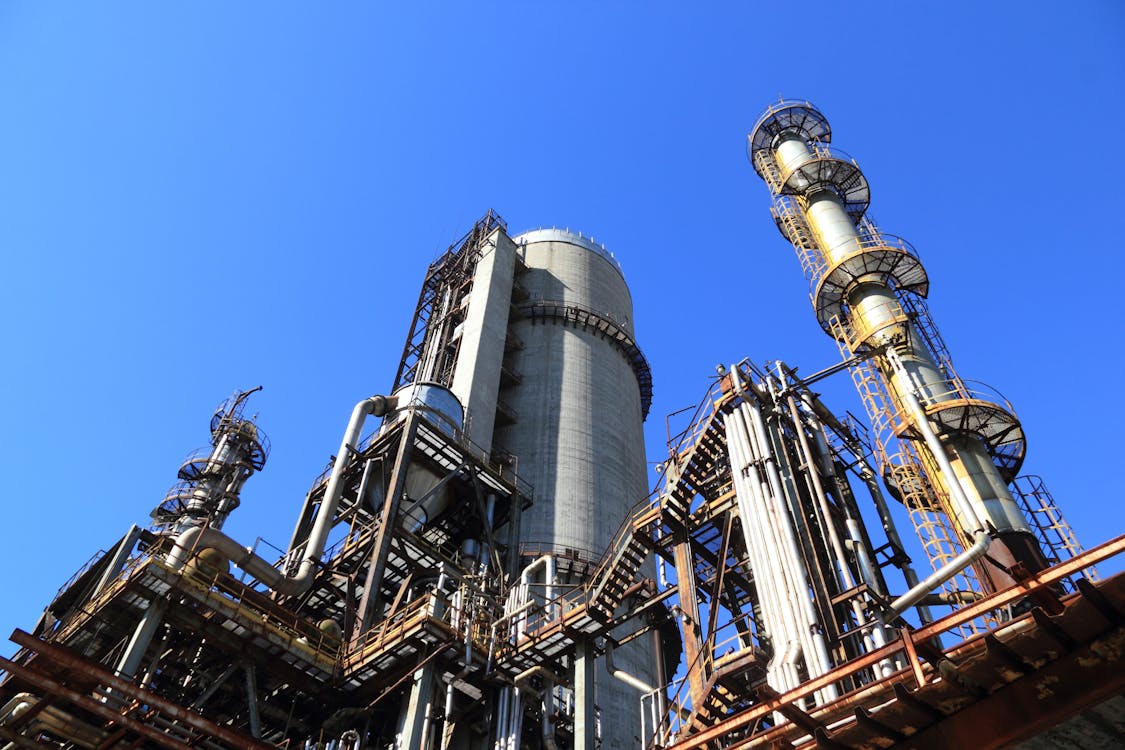 Low-angle view of an industrial manufacturing plant with towers, piping, and steel structures